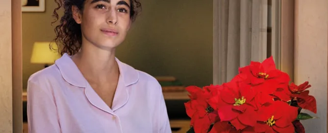 Donna con stella di Natale al davanzale di una finestra - Campagna AIL Natale 2025